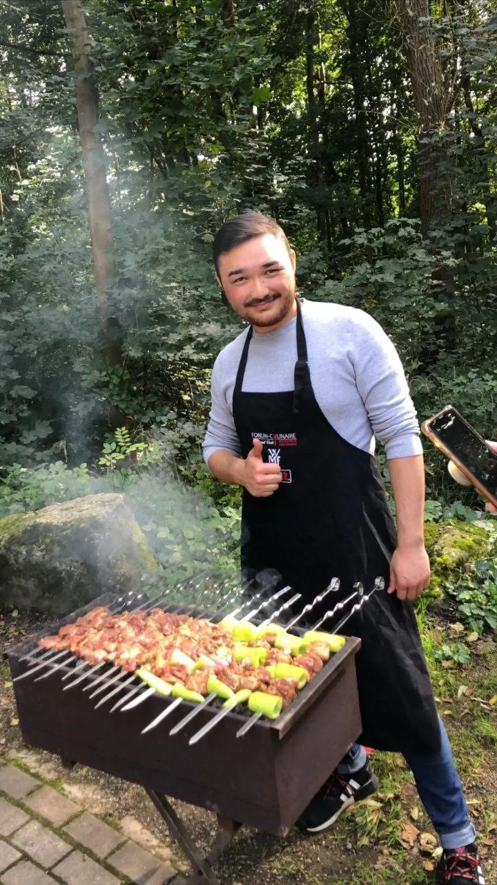 Ein junger Mann grillt Schaschlik-Spieße im Wald
